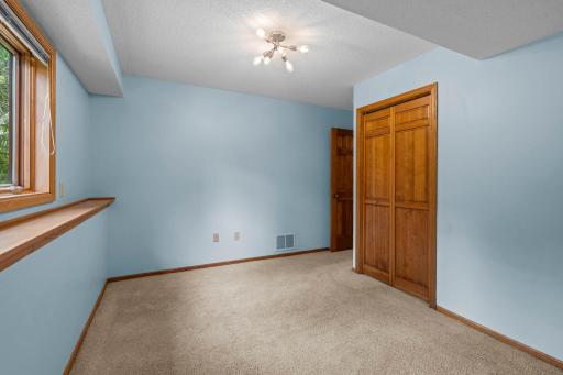 Alternate view of the third bedroom highlighting the solid wood bifold closet doors and unique multi-bulb light fixture.