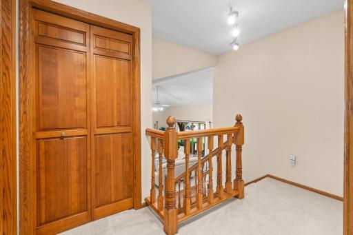 Upper-level hallway landing with solid wood bifold closets and a classic timber railing overlooking the main floor.