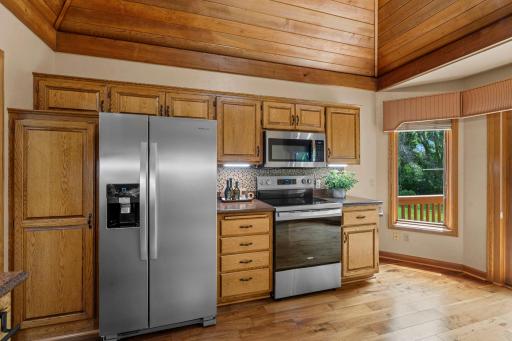 Alternate kitchen view highlighting the striking vaulted wood ceiling and modern under-cabinet lighting.