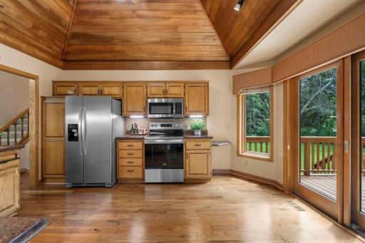 Spectacular kitchen boasting a striking wood-clad vaulted ceiling, stainless steel appliances, and sliding doors to the deck.