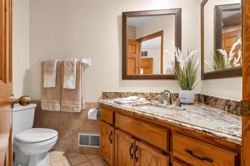 Updated primary en suite bathroom featuring a classic oak vanity and rich granite countertops.