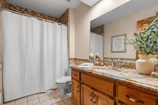 Bright upper-level full bathroom featuring tile flooring, a shower/tub combination, and a rich granite vanity top.