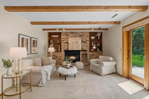 Inviting garden-level living space with built-in shelving flanking a classic floor-to-ceiling brick hearth.