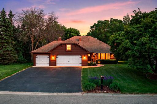 Stunning twilight view highlighting the warm, inviting curb appeal and beautifully illuminated 3-car garage.
