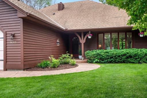 Close-up of the inviting front porch area, complete with decorative architectural brackets and neat landscaping.