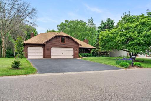 Welcoming street-level view featuring the wide asphalt driveway and charming curb appeal.