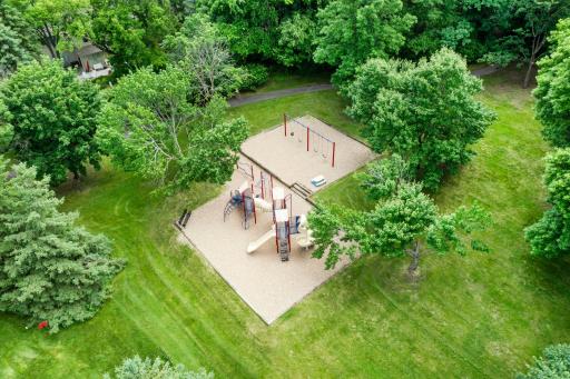 Overhead perspective of the park area, showcasing the clean playset and swing set installations surrounded by expansive lawn space.