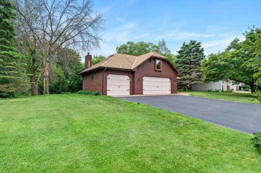 Side profile highlighting the deep setback, spacious 3-car garage, and lush green yard space.