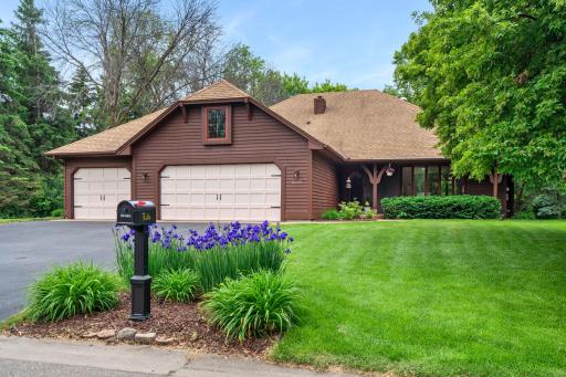 Detailed front view drawing attention to the charming stone-bordered flower beds and pristine lawn care.