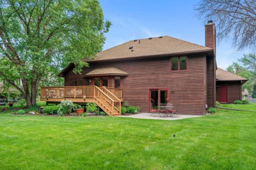 Beautiful backyard setting featuring a spacious entertainment deck, lower concrete patio, and lush green lawn.