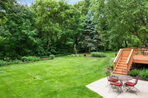 Beautifully manicured, flat green lawn area bordered by a dense canopy of mature trees for ultimate privacy.