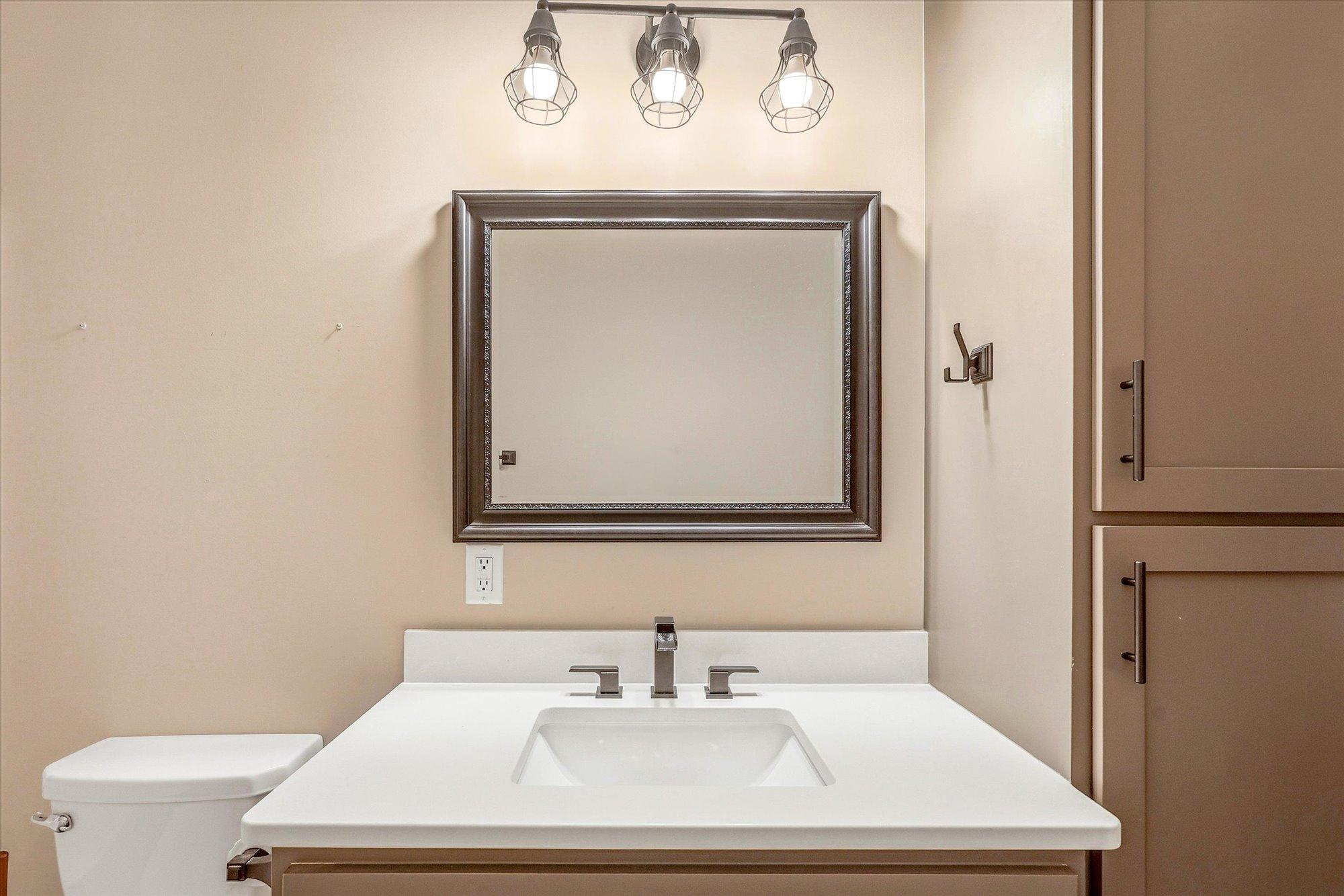 Clean-lined vanity with solid surface countertop and modern lighting adds a polished touch to the lower-level bath.