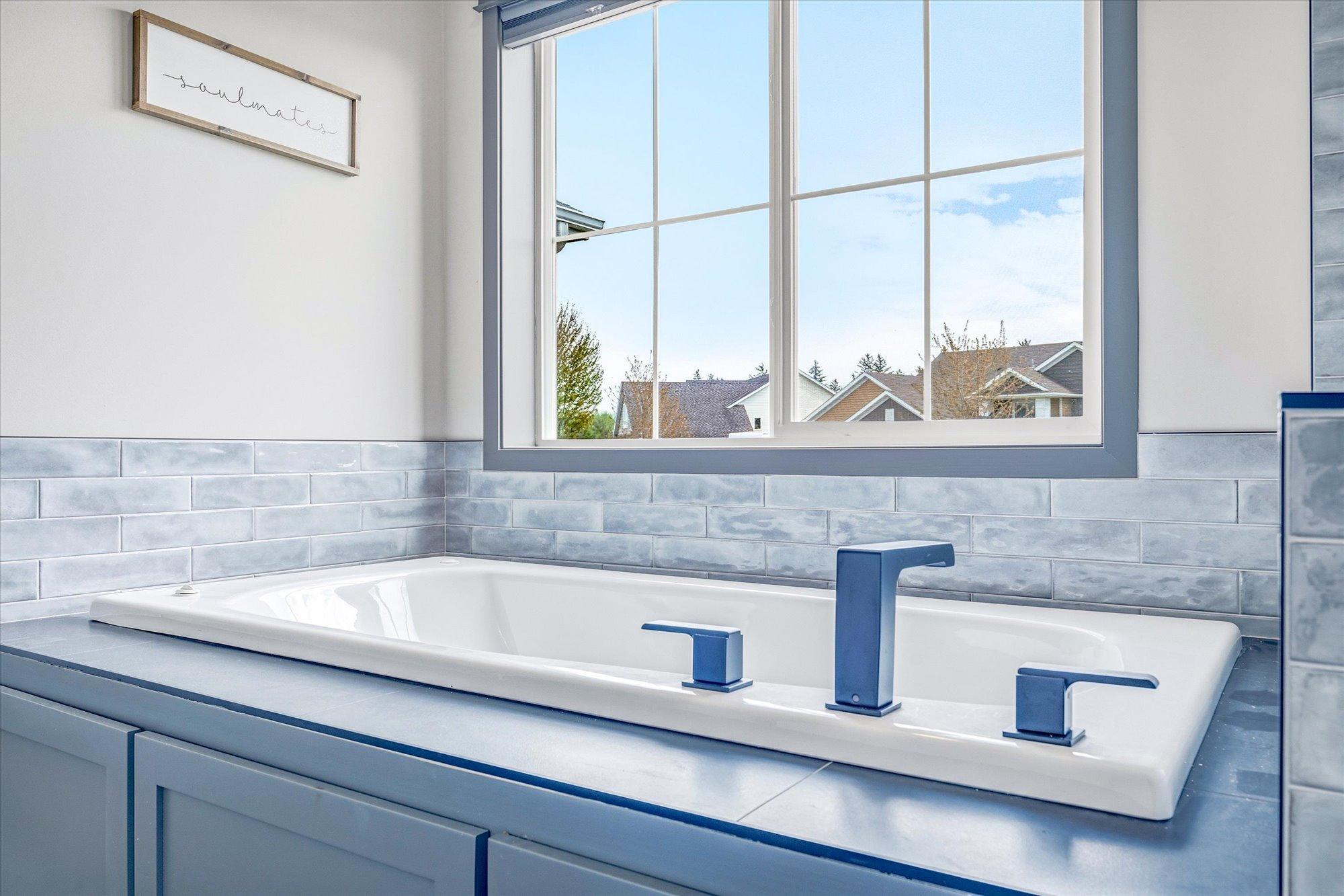 Relax and unwind in the soaking tub positioned beneath a large window for abundant natural light.