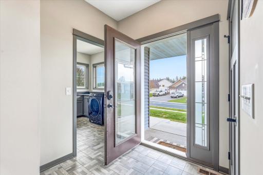 Bright and welcoming foyer with stylish tile flooring, tall ceilings, and modern gray trim and doors throughout. Front entry showcases beautiful natural light and easy access to the spacious laundry and mudroom area.