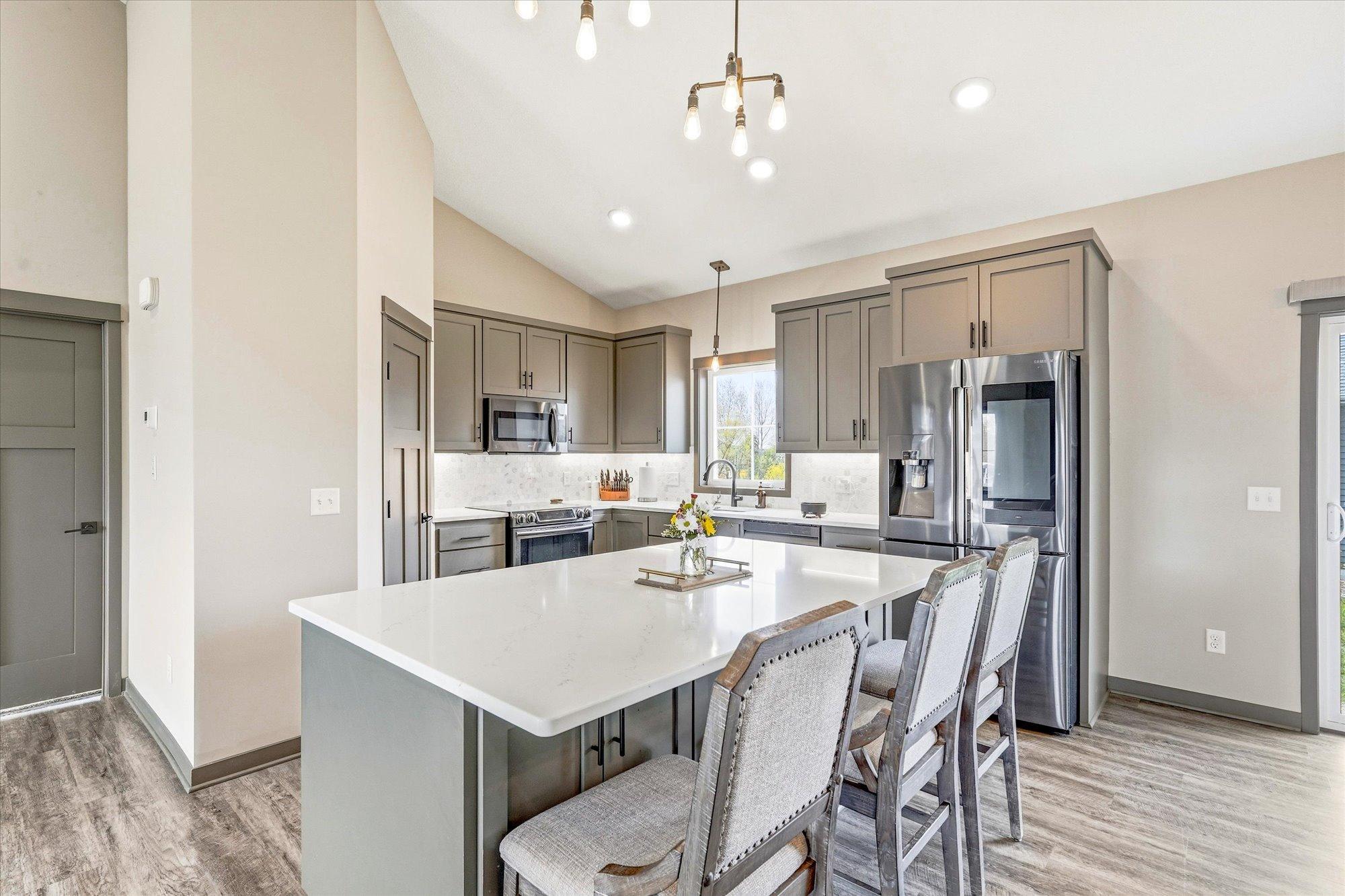 Gorgeous kitchen featuring quartz countertops, oversized center island with seating, stainless steel appliances, and custom cabinetry.