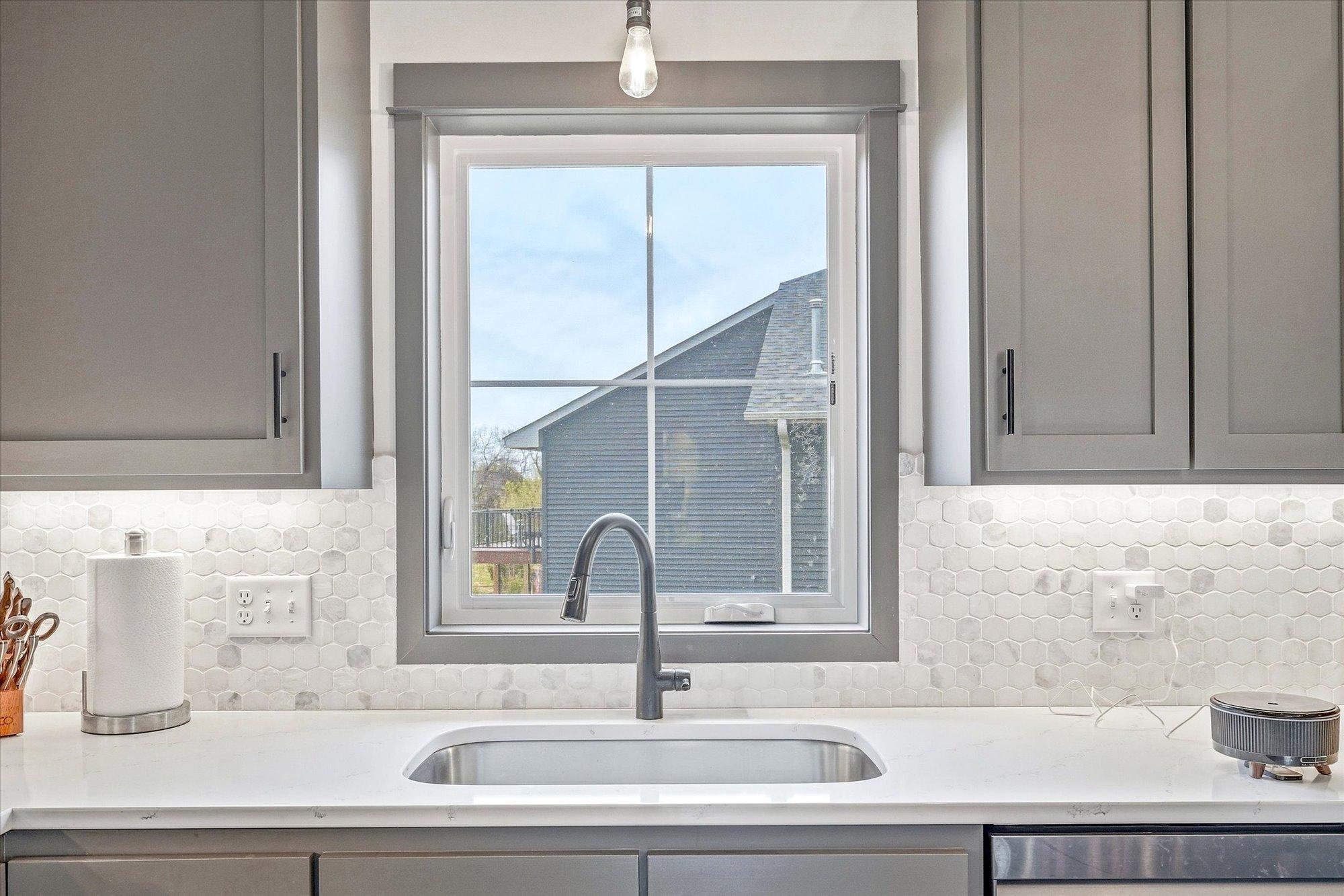 Large kitchen window fills the space with natural light while highlighting the attractive backsplash and modern farmhouse finishes.