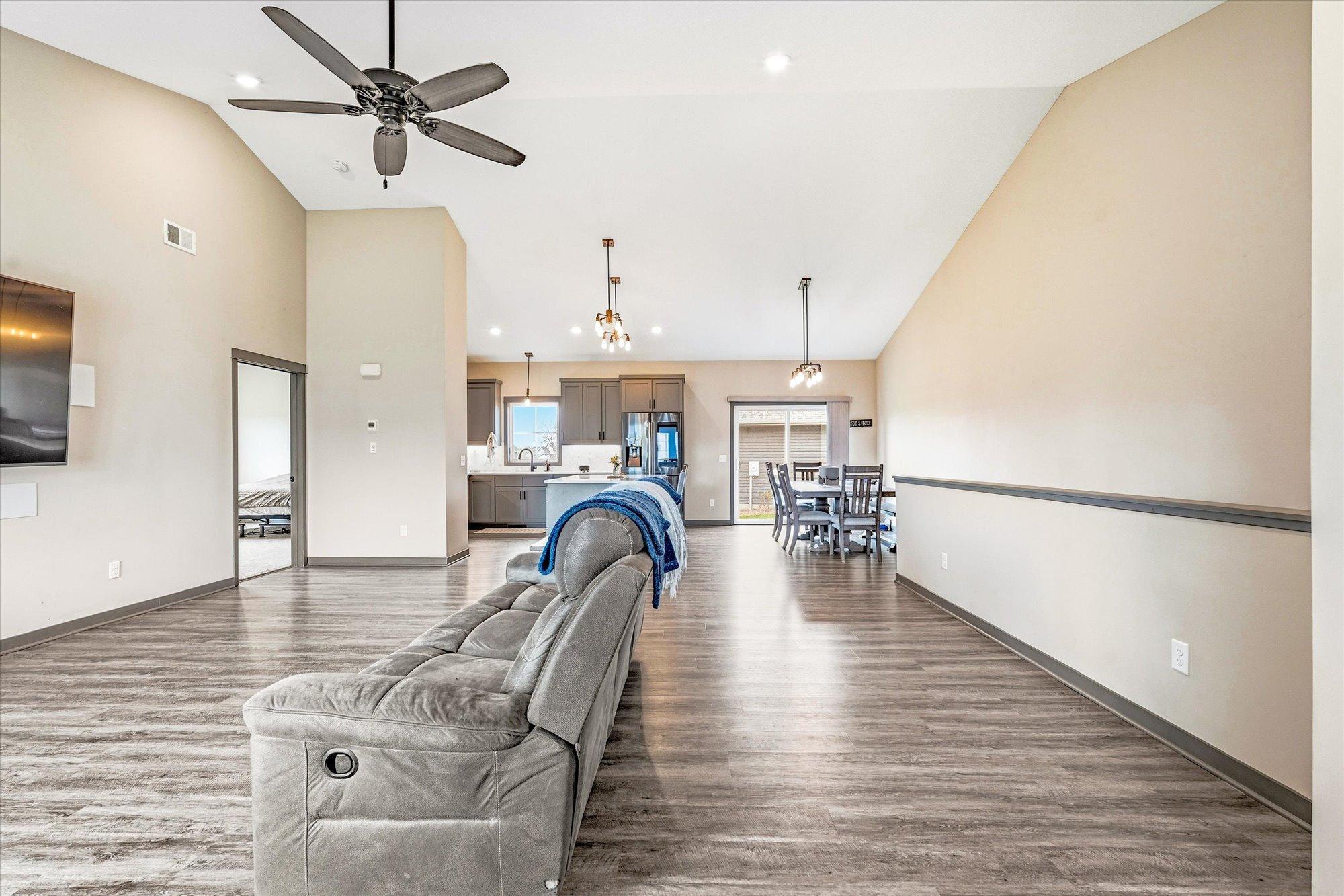 Expansive open-concept main living area with soaring vaulted ceilings, luxury flooring, and abundant natural light throughout.