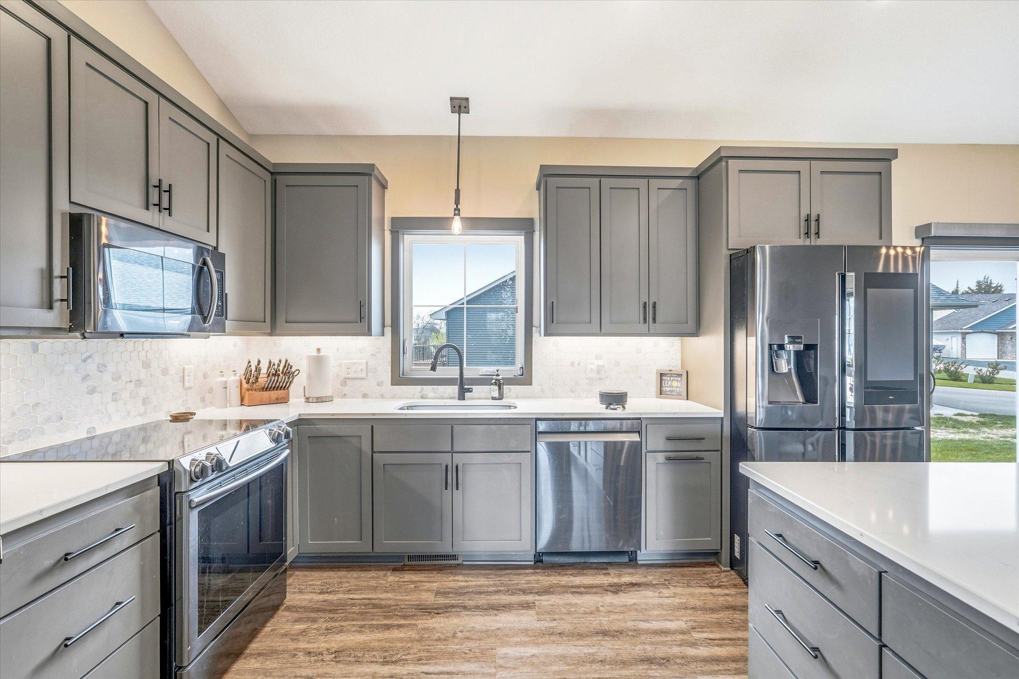Designer kitchen showcases custom gray cabinetry, quartz countertops, stainless steel appliances, and stylish modern finishes throughout.
