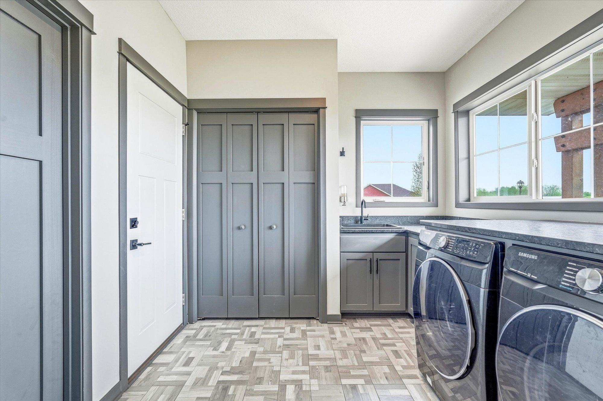 Large laundry and mudroom with abundant cabinetry, utility sink, and oversized windows for great natural light.