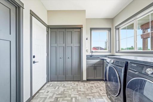 Large laundry and mudroom with abundant cabinetry, utility sink, and oversized windows for great natural light.