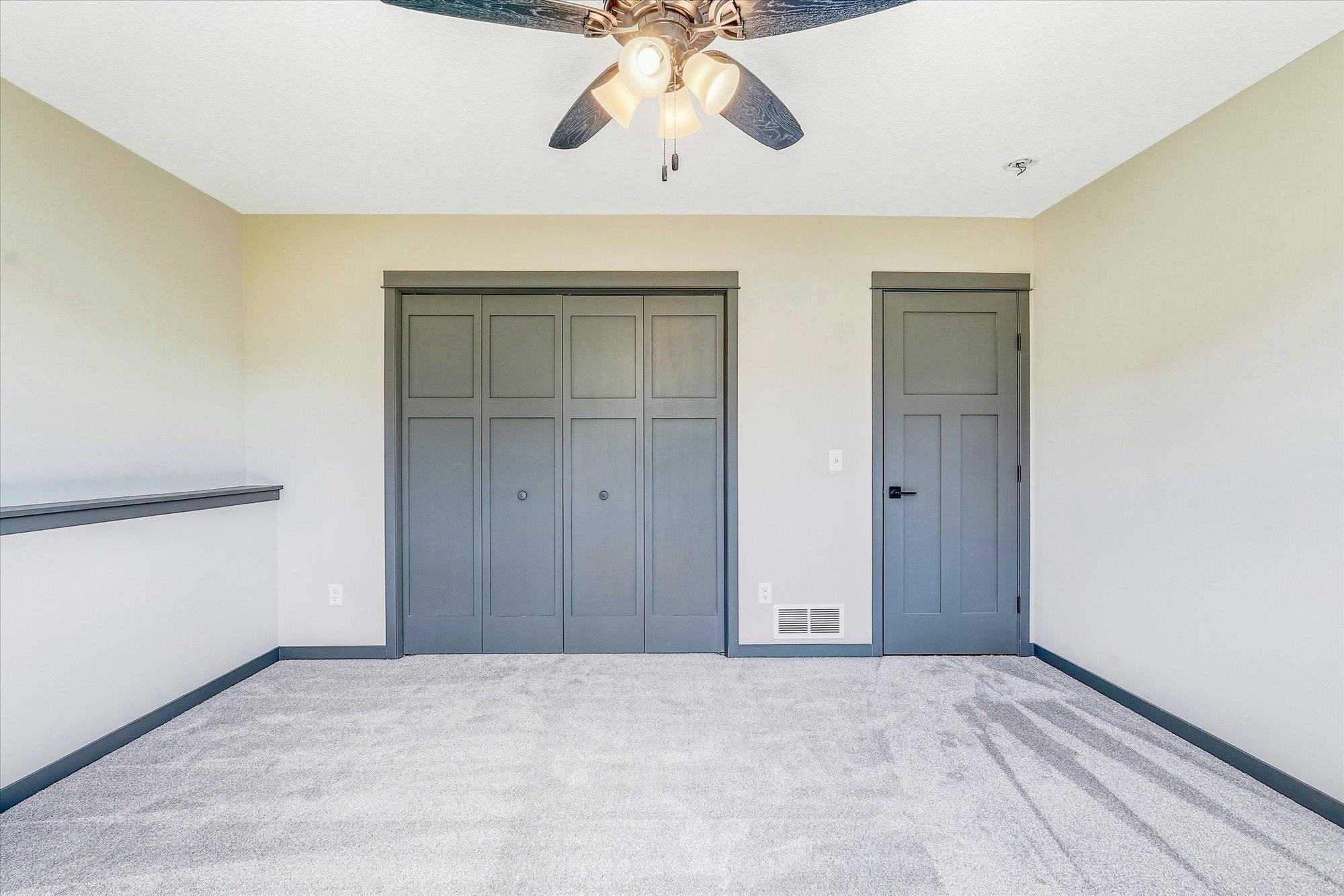Spacious lower-level bedroom features plush carpeting, stylish gray trim, and oversized closet doors for excellent storage.