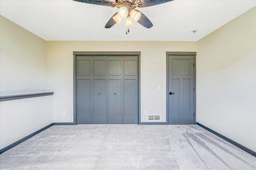 Spacious lower-level bedroom features plush carpeting, stylish gray trim, and oversized closet doors for excellent storage.