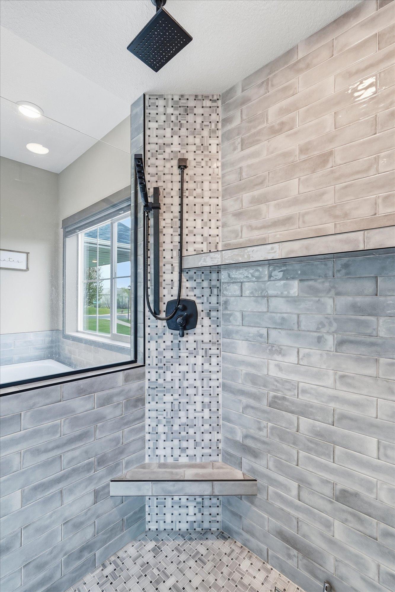 Beautiful custom tilework and upgraded black fixtures create a luxurious modern shower experience.