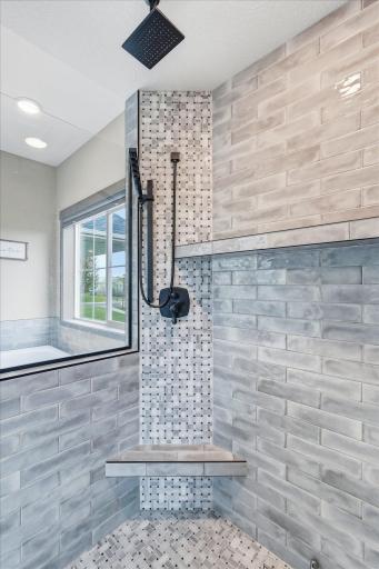 Beautiful custom tilework and upgraded black fixtures create a luxurious modern shower experience.