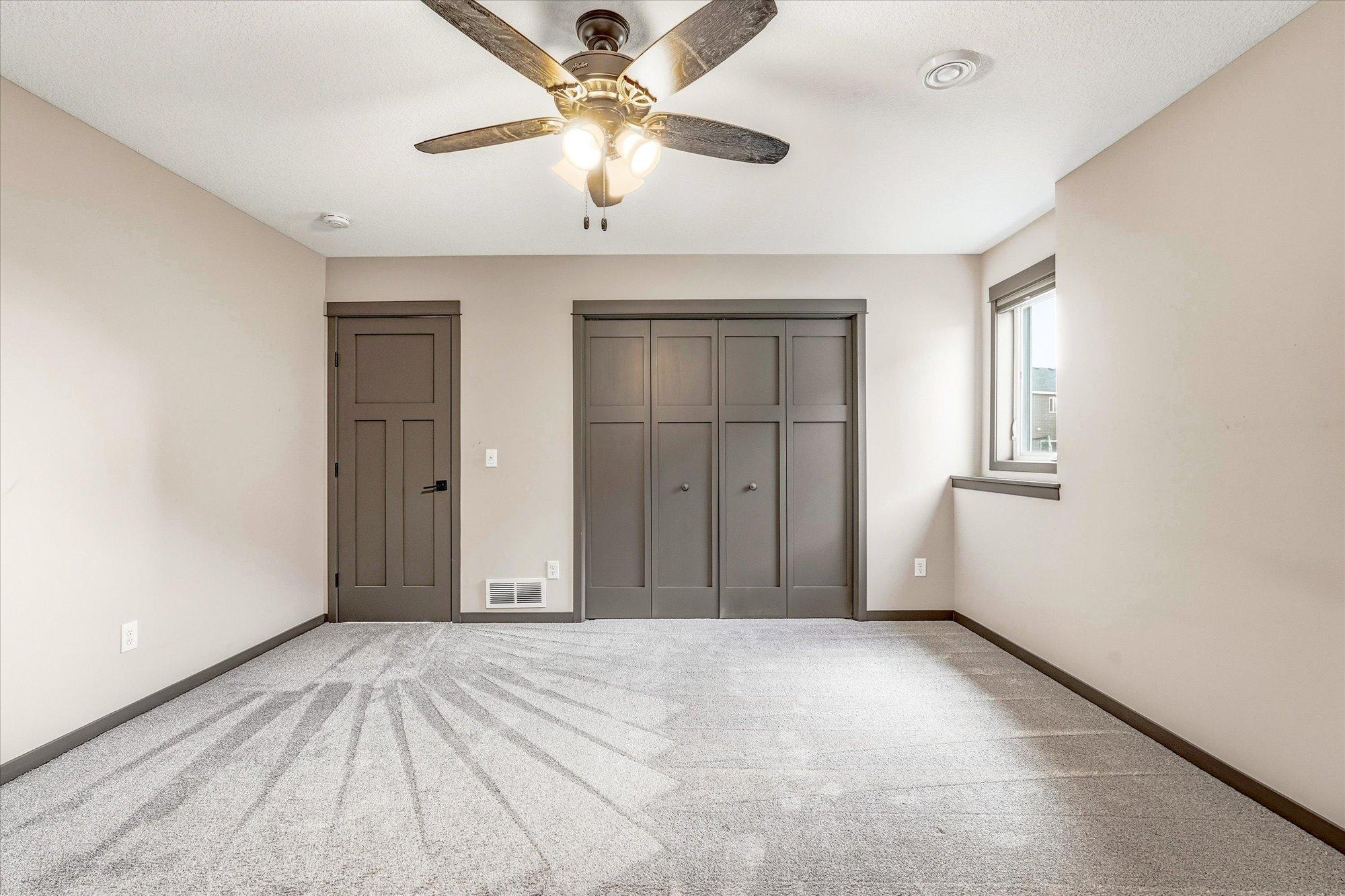 Additional lower-level bedroom includes neutral finishes, abundant natural light, and ample closet space.