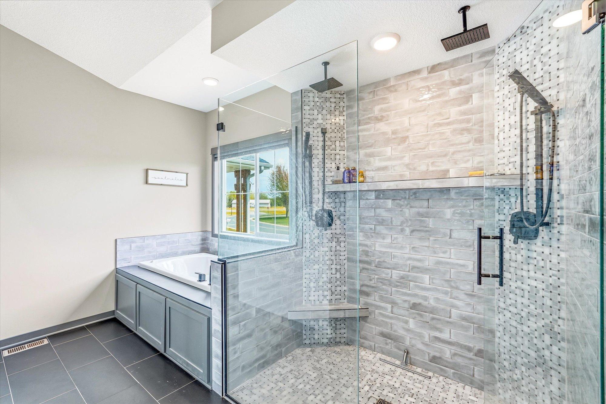Spa-like primary bathroom features a stunning walk-in tiled shower with dual shower heads, bench seating, and sleek glass surround.