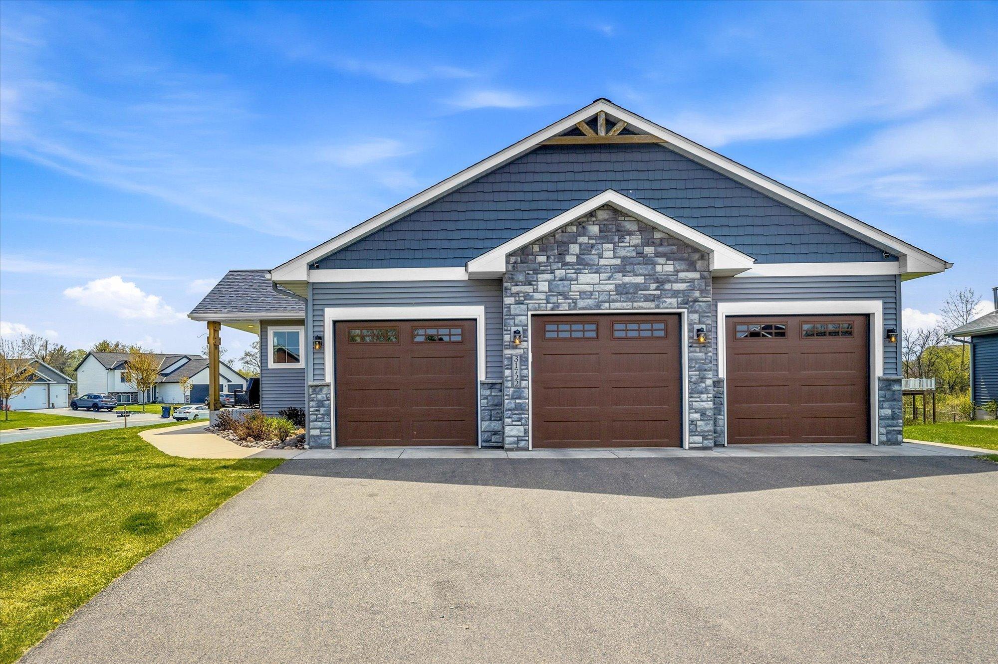 Beautifully designed exterior featuring maintenance-free siding, stone details, architectural peaks, and a welcoming front entry. Spacious three-car attached garage with attractive carriage-style doors offers excellent storage and curb appeal.