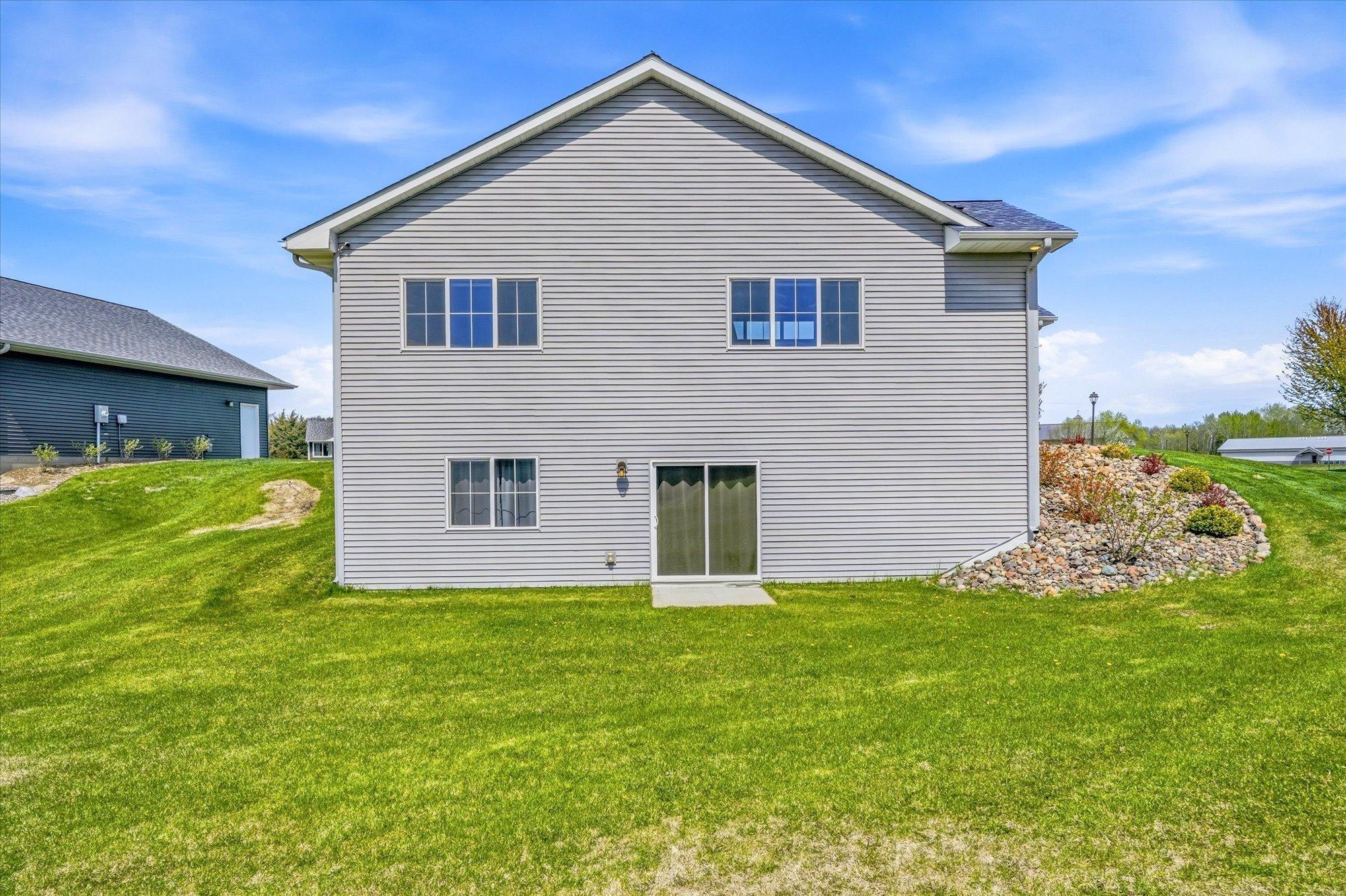 Rear exterior showcases the home’s spacious footprint, walkout design, and beautifully maintained lot.