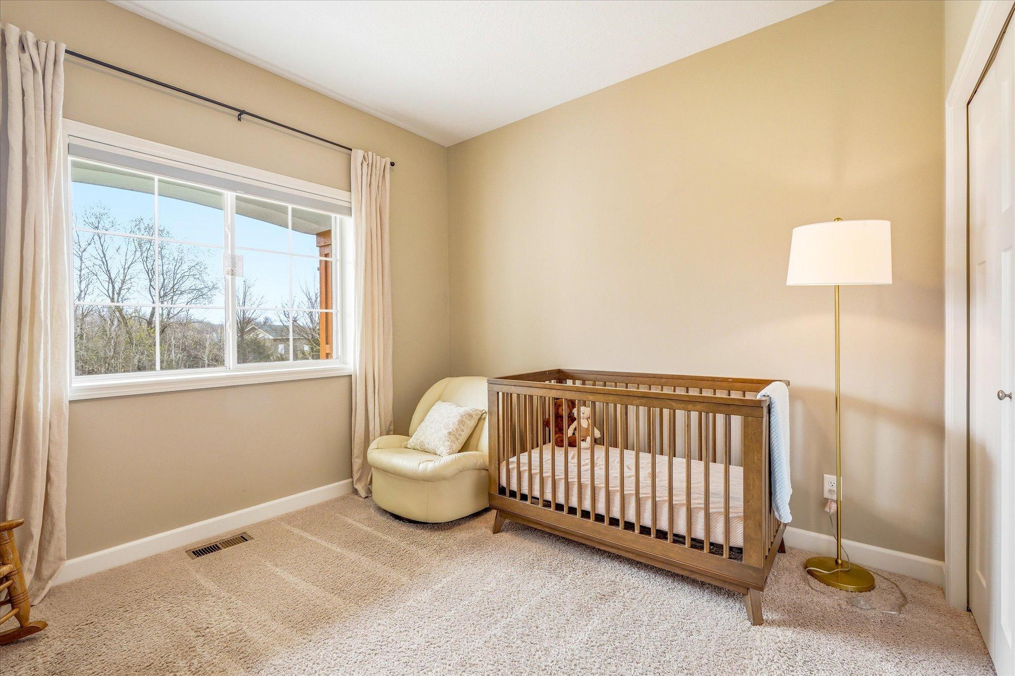 The second bedroom on the main level features views of trees and room darkening shades to keep the room cool during the summer months. The window looks out to a wooded area across the street.