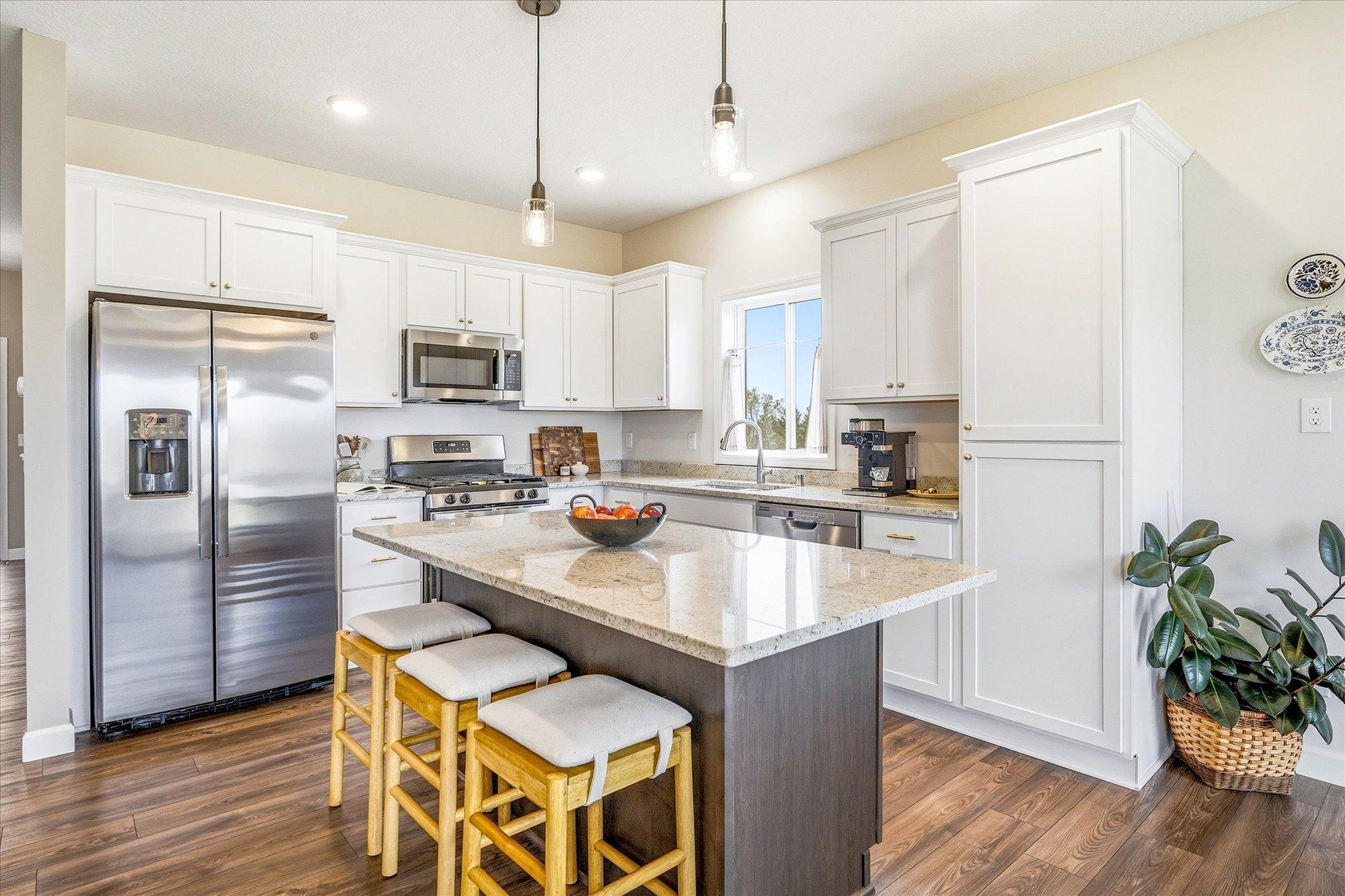 The kitchen gleams with its two toned cabinets and seating for four at the island.
