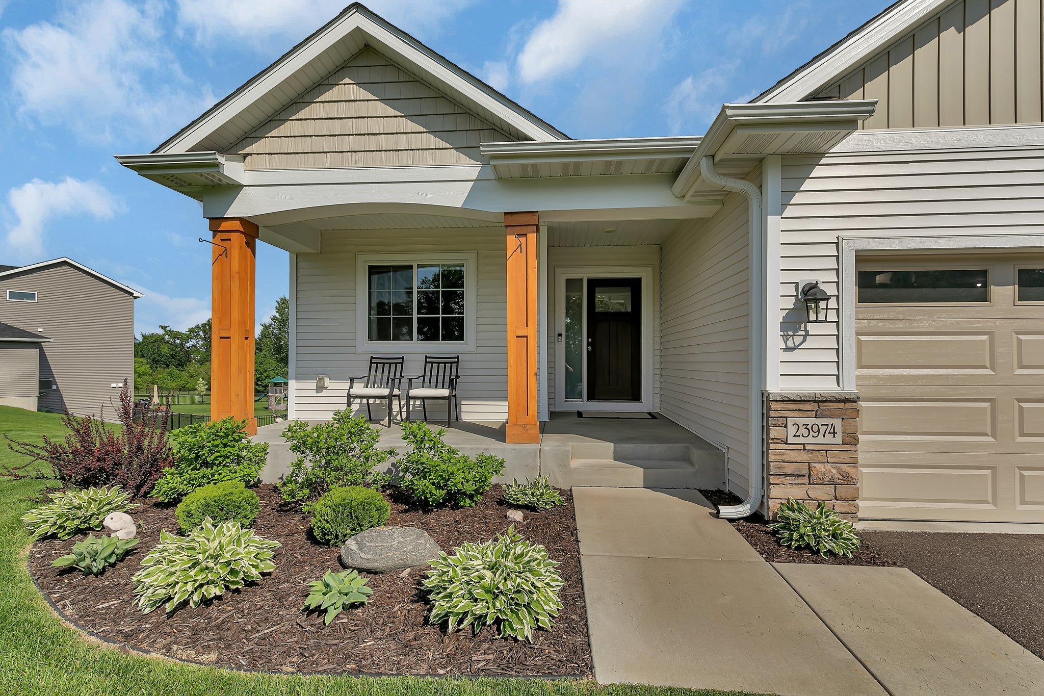 The inviting front porch features timber posts and low maintenance landscaping. This photo shows the perennials that come back to life every year giving you a low-maintenance yard.