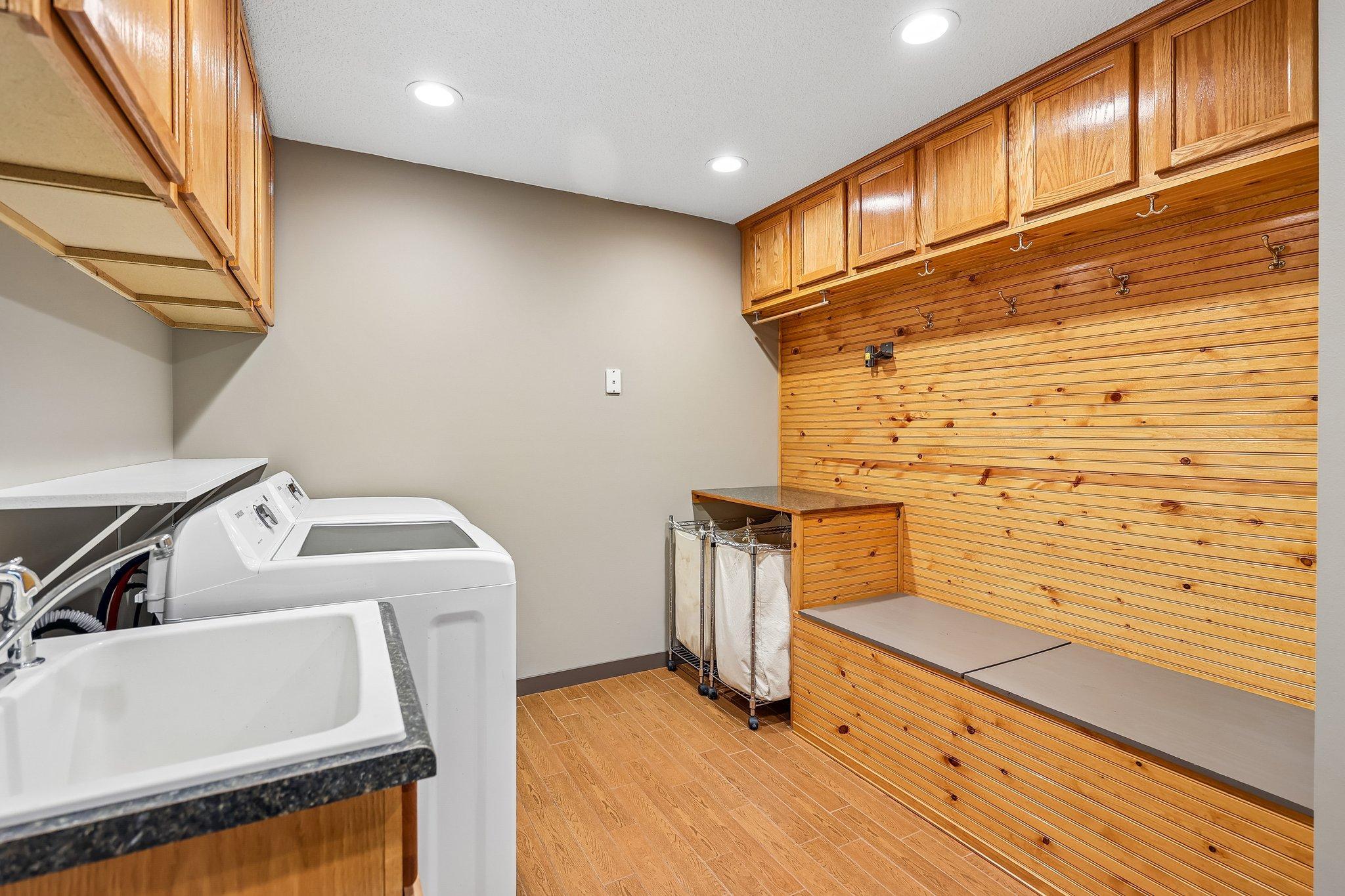 Laundry with storage, cabinets, newer flooring, recessed lights, sink and bench!