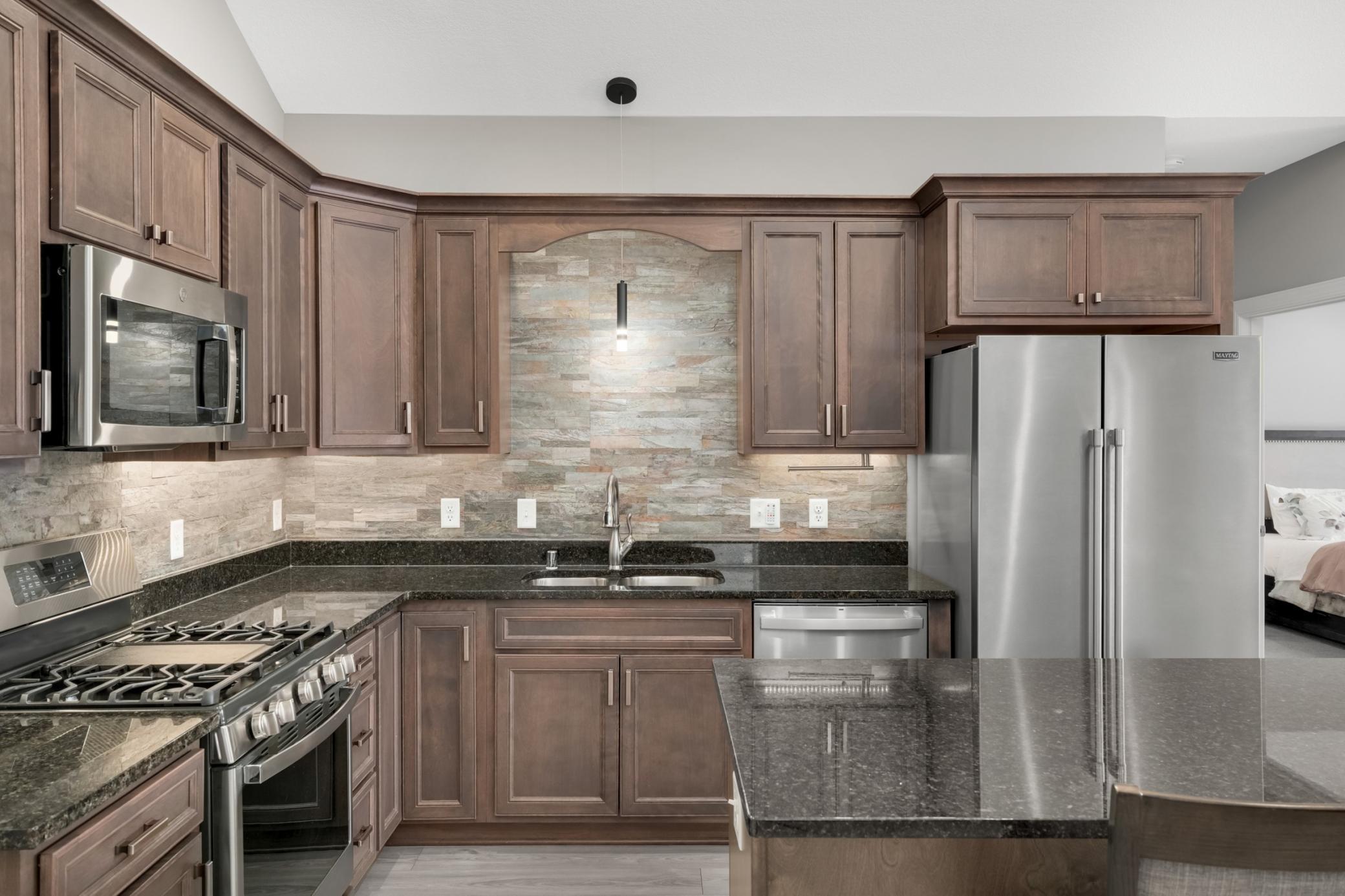 Kitchen features birch cabinets, granite counters, quartz backsplash, under cabinet lighting and stainless steel appliances