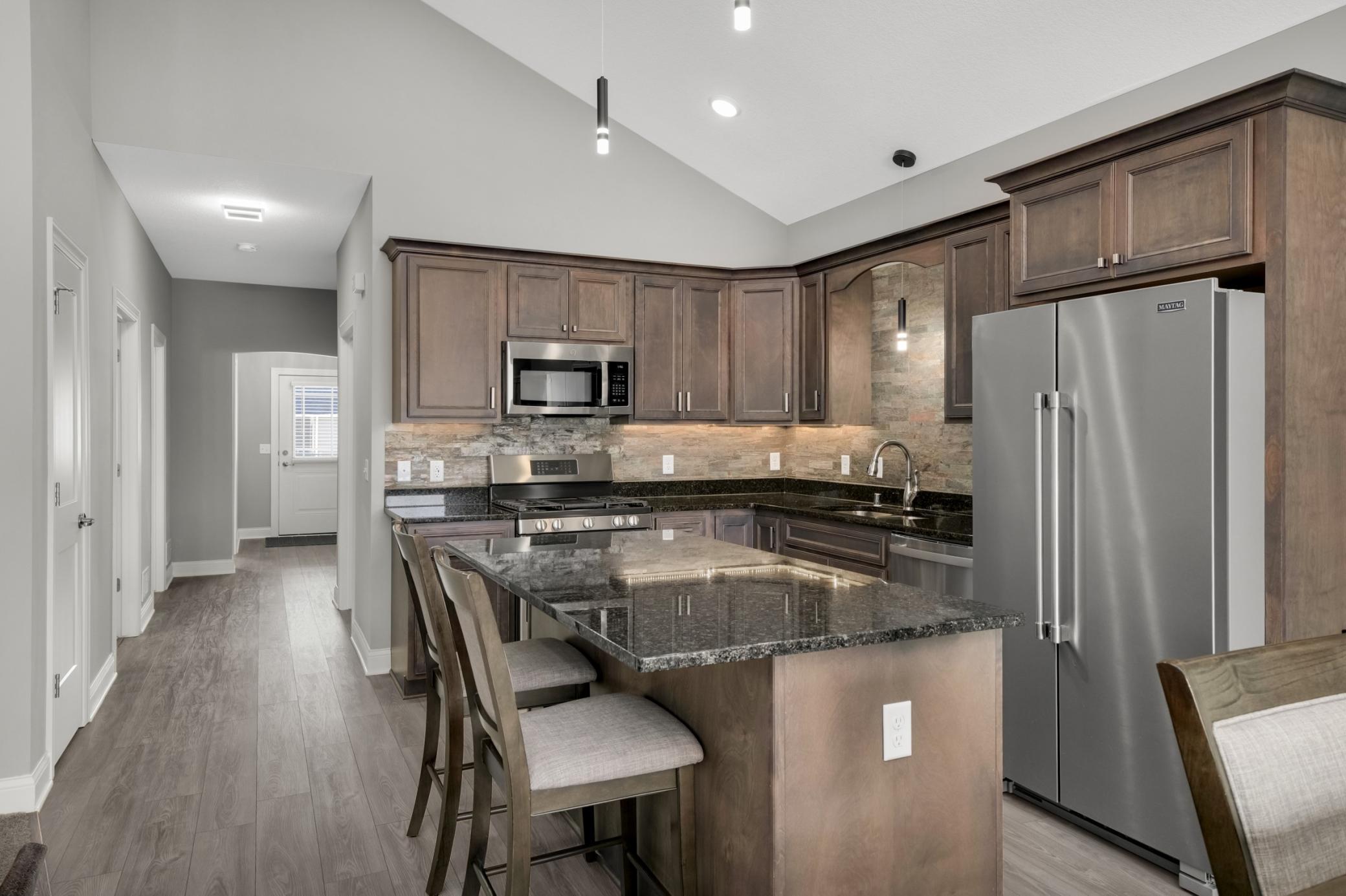 Kitchen features birch cabinets, granite counters, quartz backsplash, under cabinet lighting and stainless steel appliances