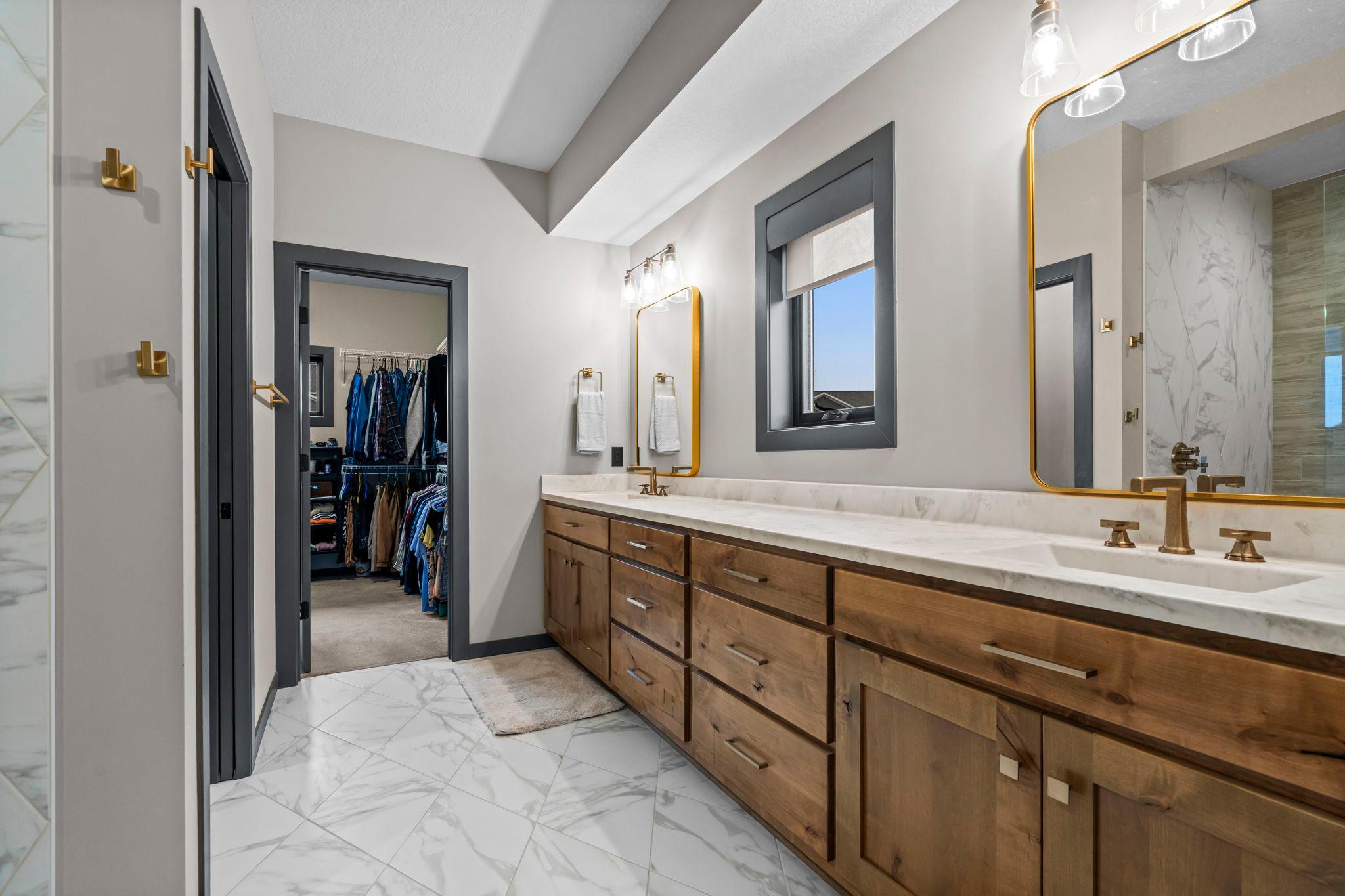 Gorgeous primary bath with double vanity, tile floors & stone counters