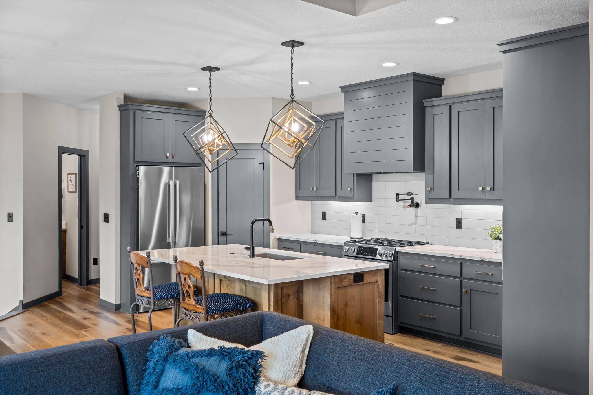 Stylish kitchen includes modern light fixtures, stone counters, gas range, stainless appliances, walk-in pantry & island offering additional seating