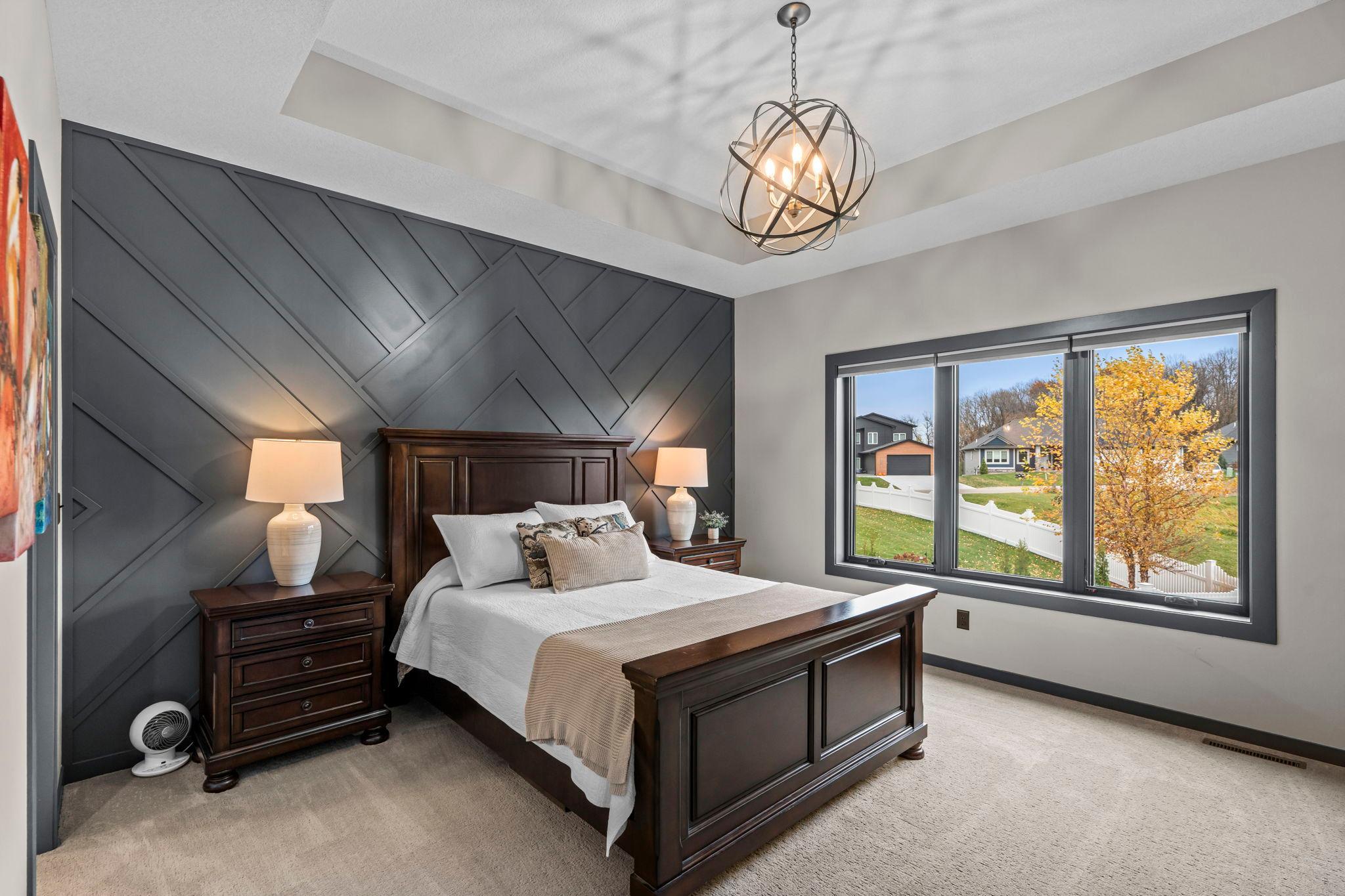 The main-level primary bedroom features a stylish accent wall and designer lighting