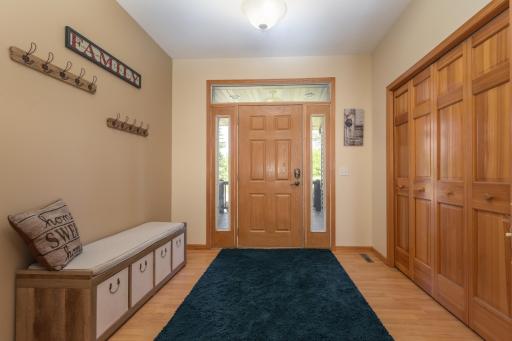 An inviting foyer welcomes you with beautiful woodwork, a practical bench and hook area, and a spacious coat closet