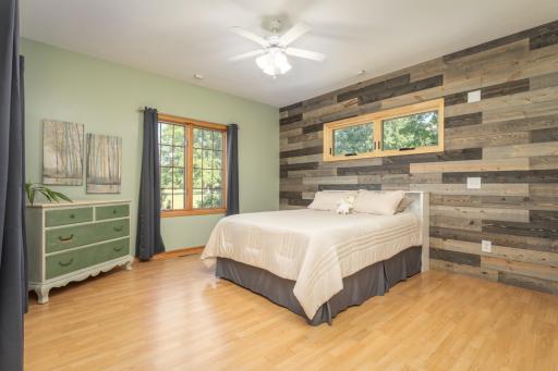 A bright and inviting main level bedroom is ready for family or overnight guests accented by a wood feature wall