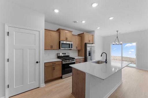 Kitchen features stained cabinets, white backsplash, black hardware with all appliances included