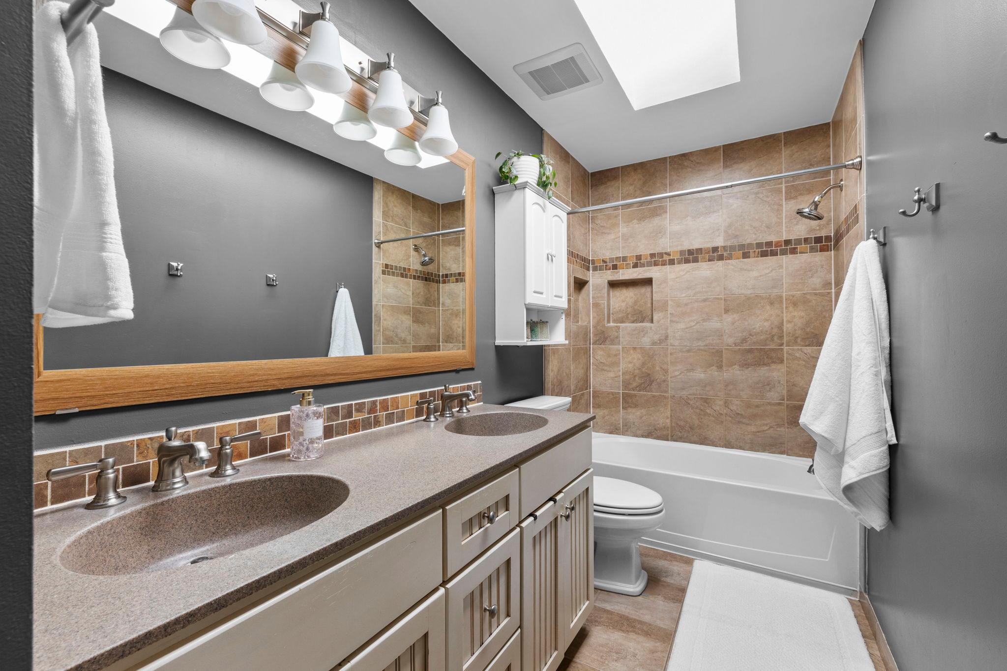 The nearby full bath is equally functional, with a double vanity, additional storage, and a skylight for added light.
