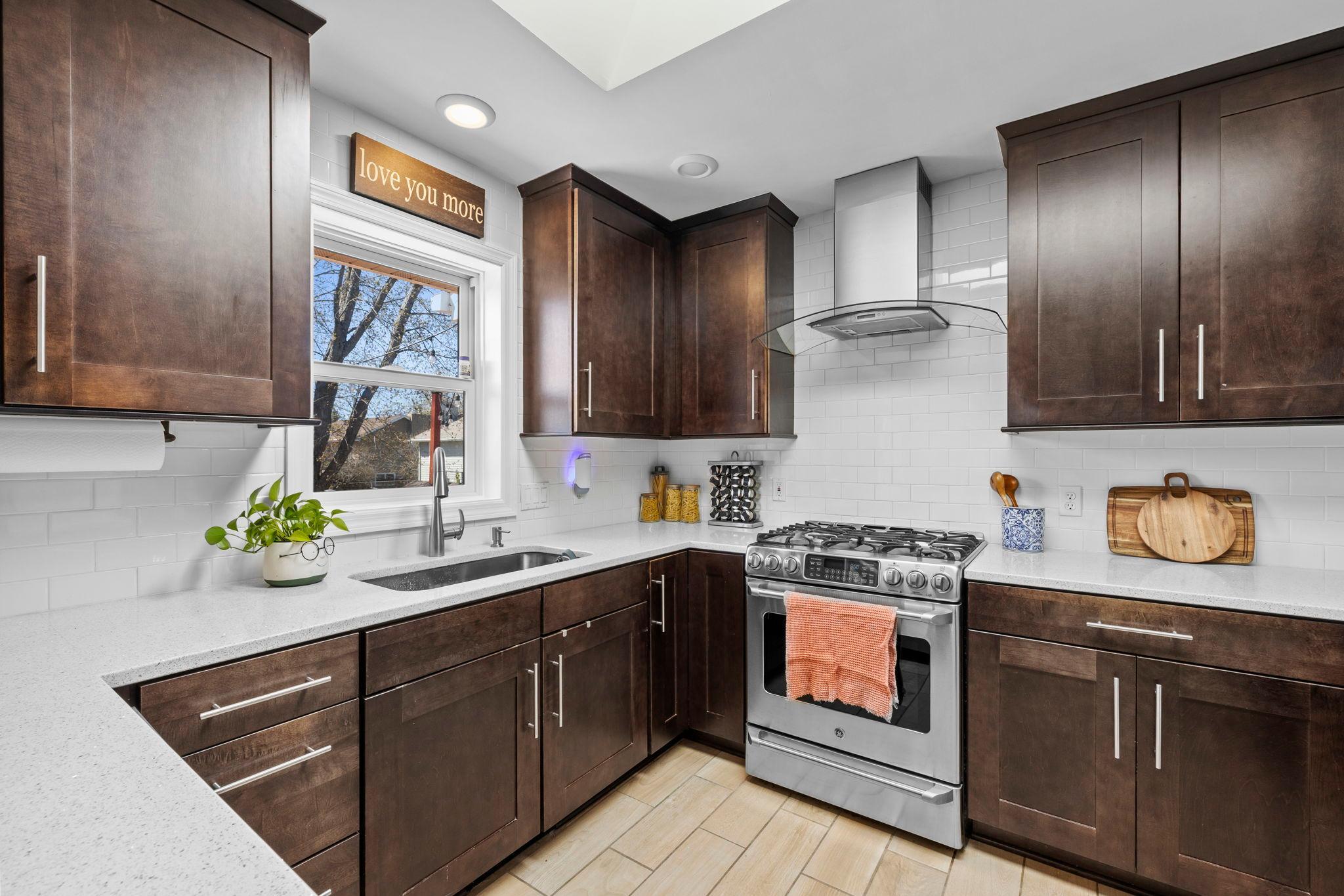 The kitchen anchors the space with rich cabinetry, a tile backsplash, and stainless steel appliances, including an updated refrigerator (2023) and dishwasher (2021).