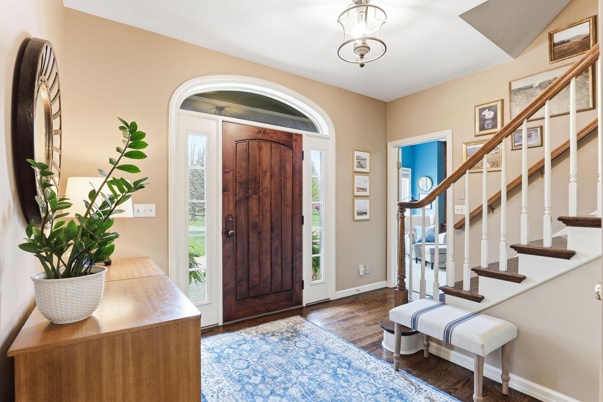 The foyer feels both luxurious and inviting, with warm hardwood floors leading into an open, light-filled space.