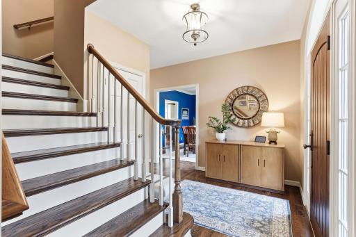 The foyer showcases sleek sophistication with its tall ceilings, gorgeous staircase, and expansive glass panels that flood the space with natural light.