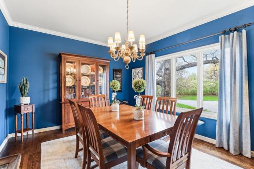 This formal dining room blends luxury with comfort, showcasing a rich hardwood floors, crown molding and large picture window allowing an abundance of natural light.