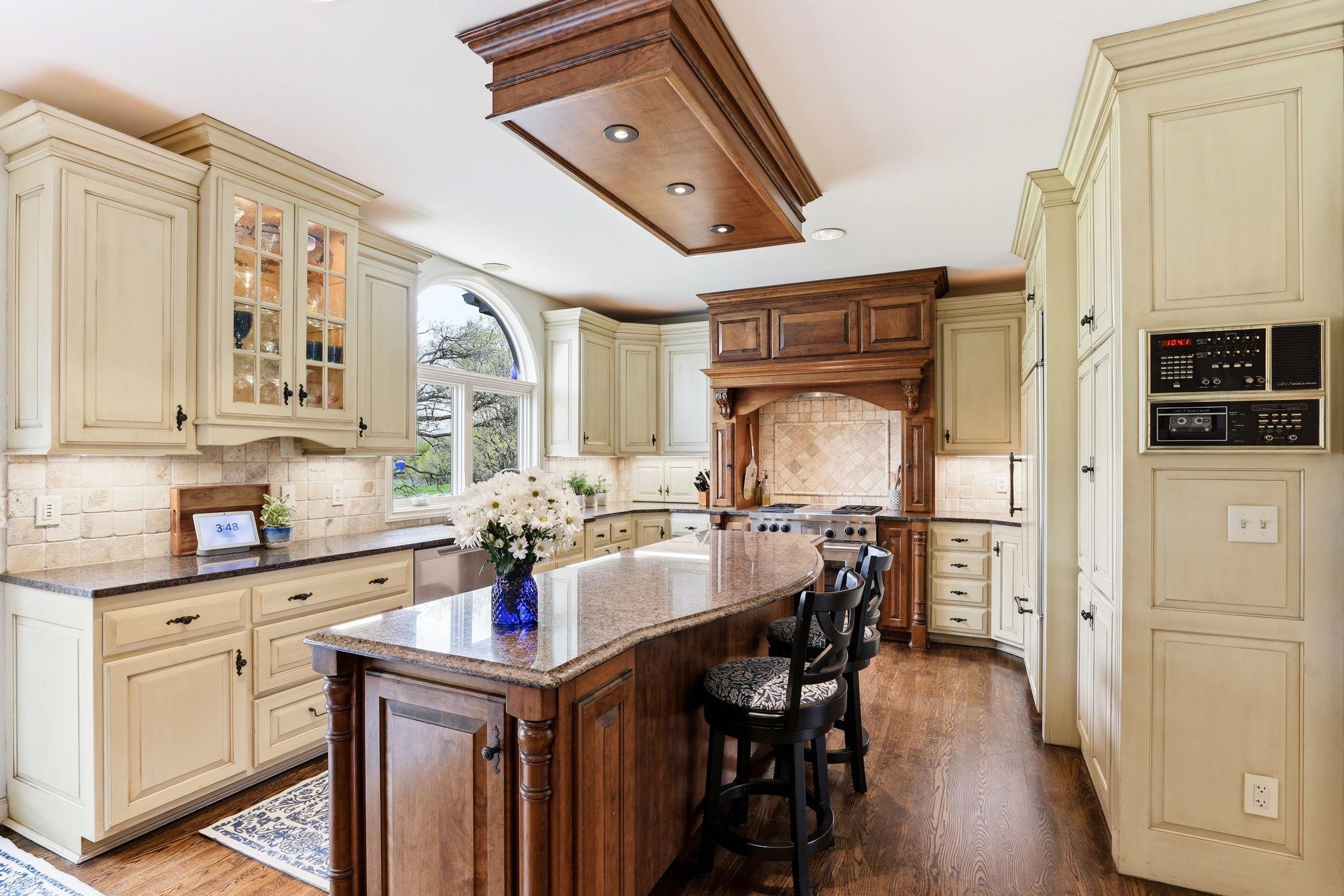 The gourmet kitchen boasts two-tone cabinetry that blends rich wood tones with crisp painted finishes for a striking, upscale look.